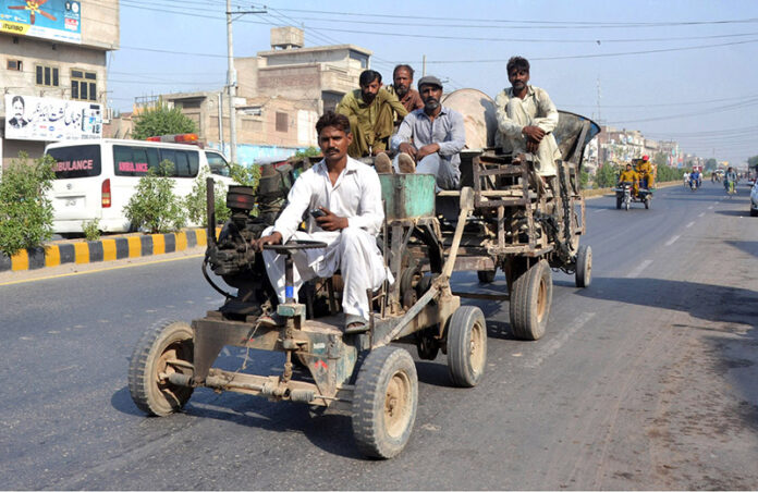Workers transport concrete mixer machine on a vehicle for construction work on the roads in the city.