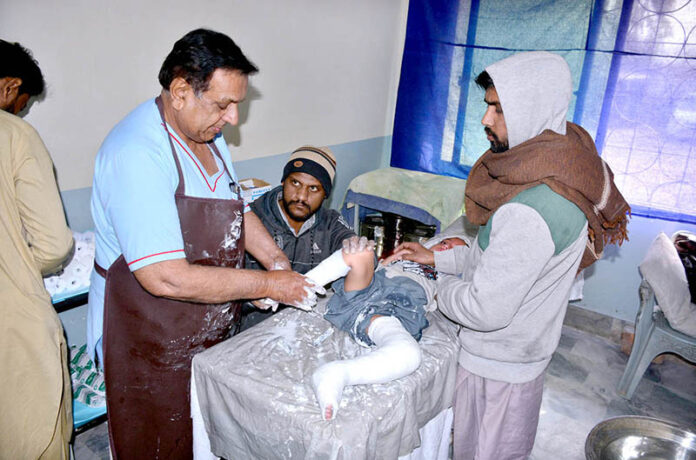 A doctor examining a child patient during Free Clubfoot Medical Camp at Trauma Center.